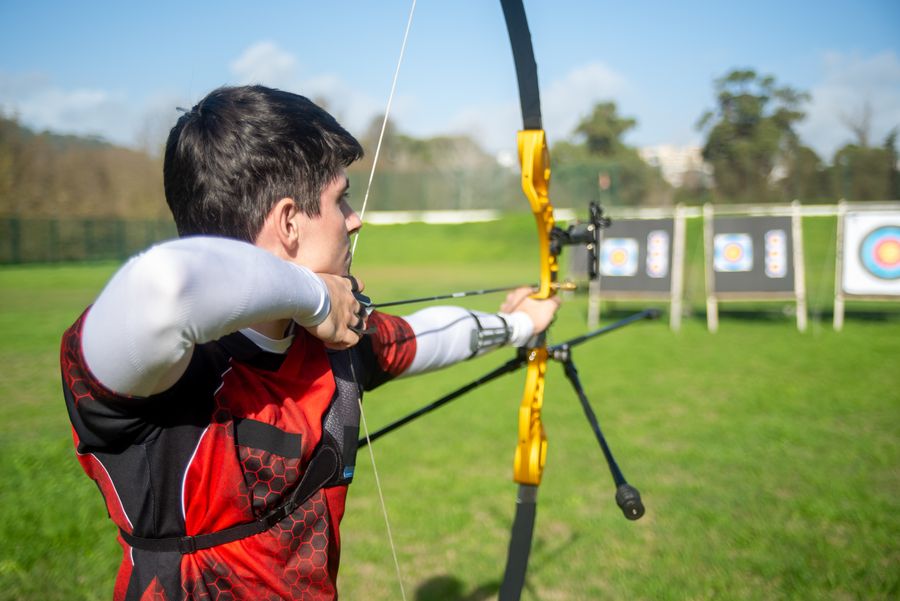 Archer at full draw, aiming downrange at distant targets