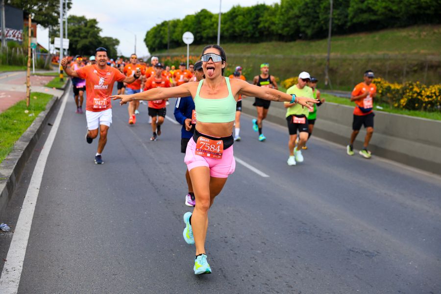 Smiling runner with arms spread wide, leading the pack in a road race