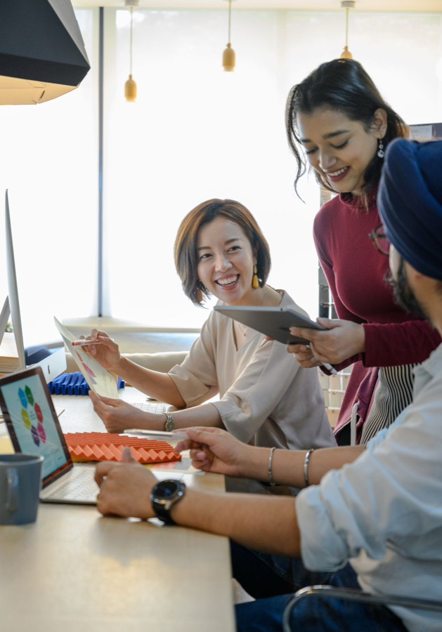 Three smiling young professionals working through ideas together