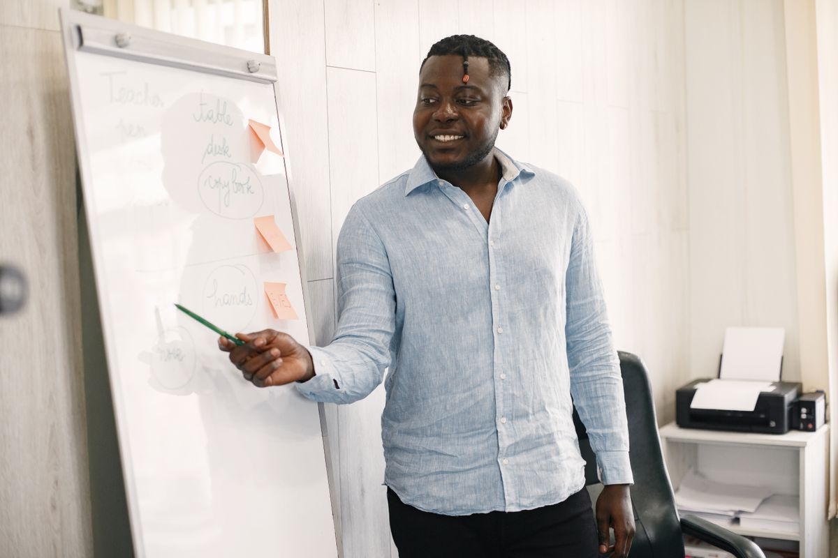 Smiling young professional in a light blue shirt presenting the next step at a flipchart